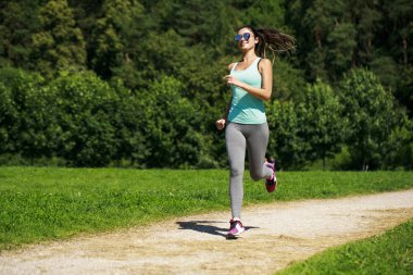 Atletik mutlu esmer kadın bir çayırda çalışma dışarı