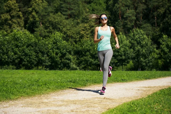 Atletica felice bruna donna che lavora in un prato — Foto Stock