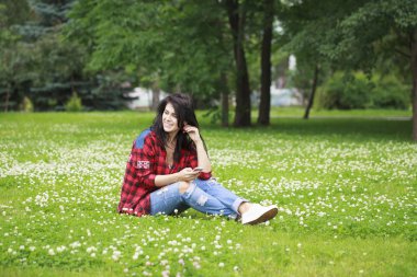 Genç kadın bir cep telefonuyla mesaj okuma çim üzerinde yalan