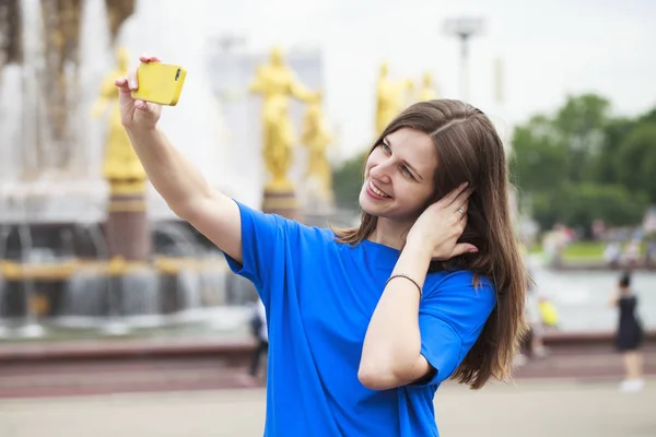 Beautiful brunette dress taking pictures of herself on a cellpho — Stock Photo, Image
