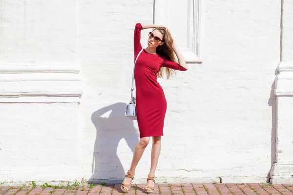 Mulher bonita em vestido vermelho sexy, contra a parede branca — Fotografia de Stock