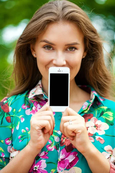 Junges schönes Mädchen zeigt ihren Smartphone-Bildschirm — Stockfoto