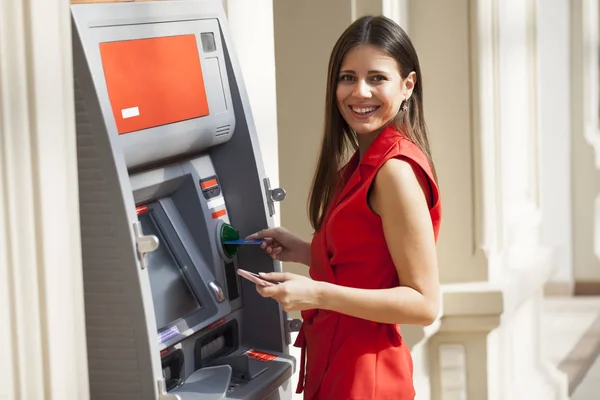 Happy woman withdrawing money from credit card at ATM — Stock Photo, Image