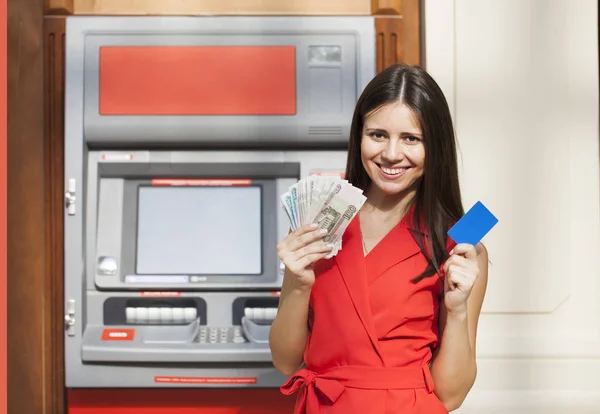 Glückliche brünette Frau hebt Geld von Kreditkarte am Geldautomaten ab — Stockfoto
