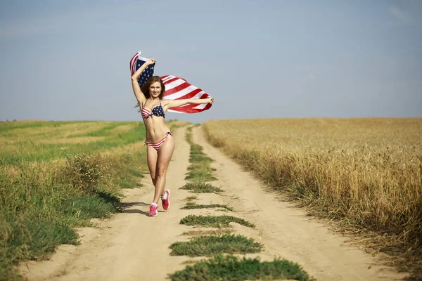 Mulher sexy em biquíni bandeira americana sexy em um campo de trigo — Fotografia de Stock