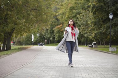 Üzerinde bej bir palto konuşmaktan mutlu genç esmer kadın portresi 