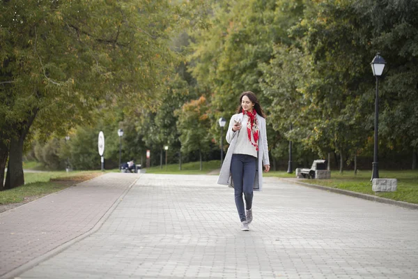 Krásná mladá brunetka žena volá telefonicky na podzim park — Stock fotografie