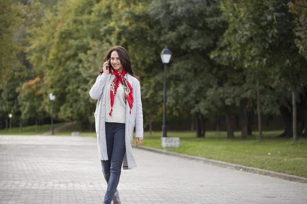 Portrait of happy young brunette woman in beige coat talking on — Stock Photo, Image