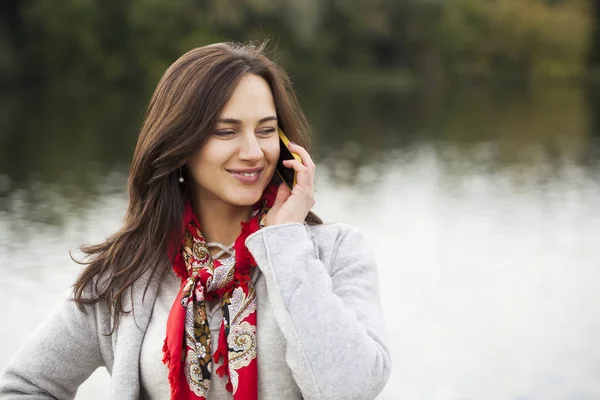 Portret van gelukkige jonge brunette vrouw beige jas om te praten over — Stockfoto
