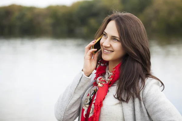 Portrait de heureuse jeune femme brune en manteau beige parlant sur — Photo