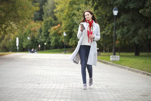 Krásná mladá brunetka žena volá telefonicky na podzim park — Stock fotografie