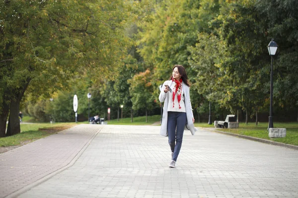 Hermosa joven morena llamando por teléfono en el parque de otoño —  Fotos de Stock