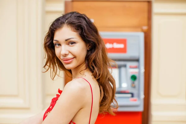 Young woman stands against the background of an ATM in a shoppin