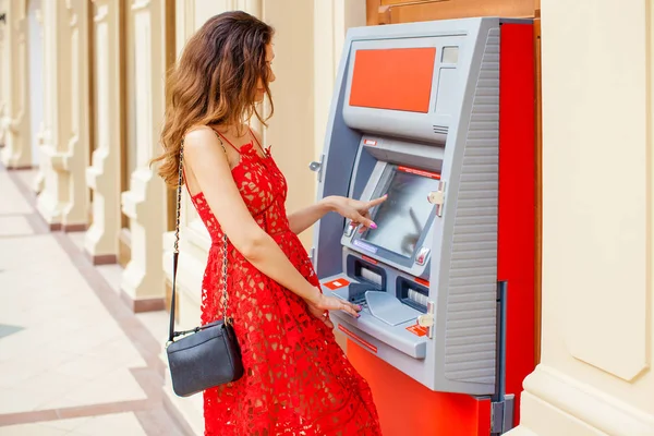 Glückliche blonde Frau hebt am Geldautomaten Geld von der Kreditkarte ab — Stockfoto
