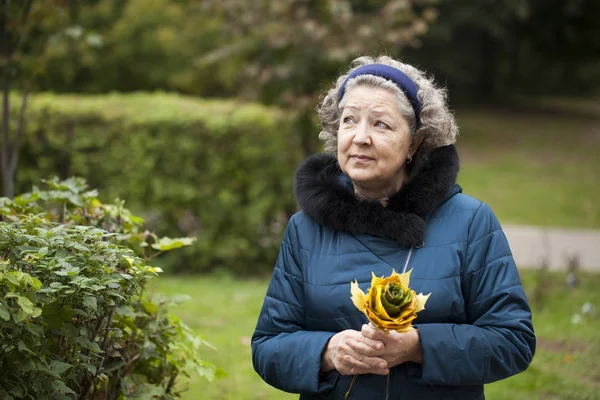 Grå vithårig äldre kvinna i en park på hösten — Stockfoto