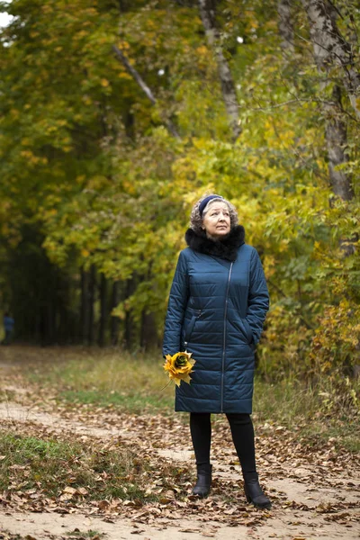 Donna anziana dai capelli grigi in un parco autunnale — Foto Stock