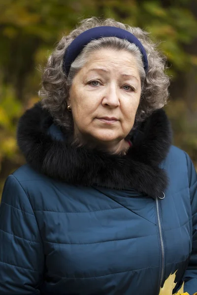 Gråhårete eldre kvinne i høstpark – stockfoto