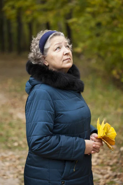 Donna anziana dai capelli grigi in un parco autunnale — Foto Stock