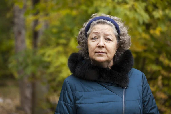 Mulher idosa de cabelos grisalhos em um parque de outono — Fotografia de Stock