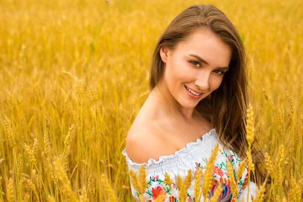 Young woman on a background of golden wheat field — Stock Photo, Image