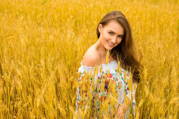 Mujer joven sobre un fondo de campo de trigo dorado — Foto de Stock