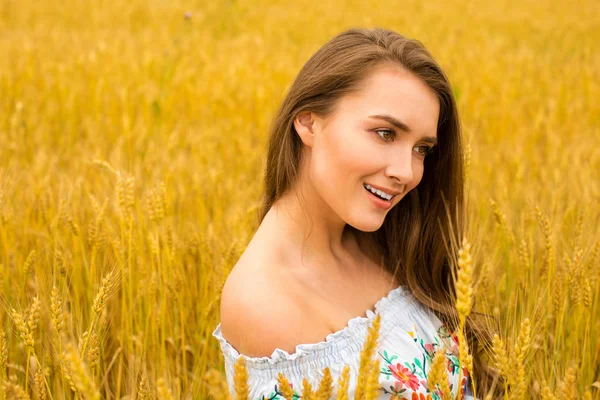 Junge Frau auf einem Hintergrund aus goldenem Weizenfeld — Stockfoto