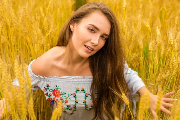 Mladá žena na pozadí zlaté pšeničné pole — Stock fotografie