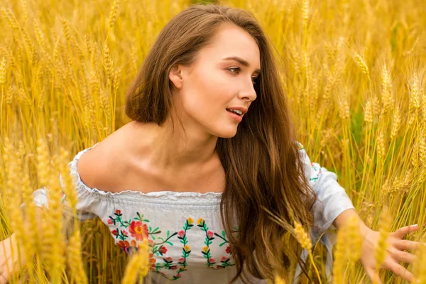 Junge Frau auf einem Hintergrund aus goldenem Weizenfeld — Stockfoto