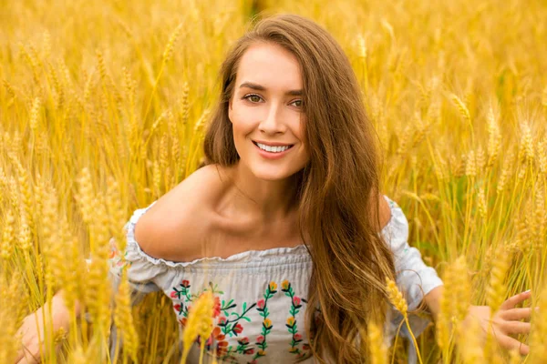 Jovem mulher em um fundo de campo de trigo dourado — Fotografia de Stock