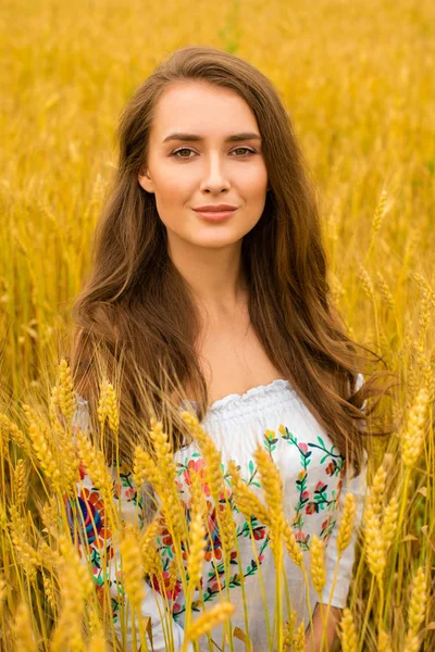 Jovem mulher em um fundo de campo de trigo dourado — Fotografia de Stock