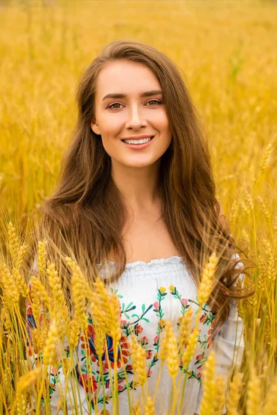 Jovem mulher em um fundo de campo de trigo dourado — Fotografia de Stock