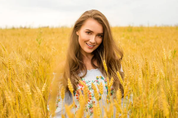 年轻的女子在金黄的麦田背景 — 图库照片