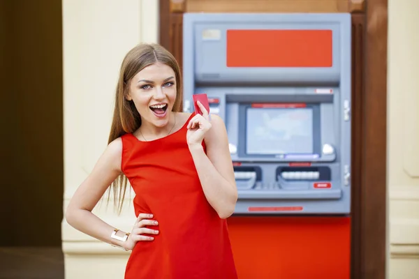 Mujer rubia feliz retirando dinero de la tarjeta de crédito en el cajero automático —  Fotos de Stock