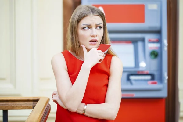 Frustrierte junge Frau tritt gegen Geldautomat — Stockfoto