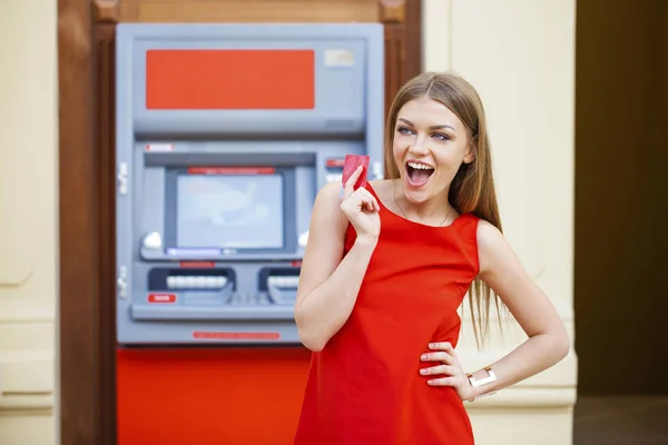 Mujer rubia feliz retirando dinero de la tarjeta de crédito en el cajero automático —  Fotos de Stock