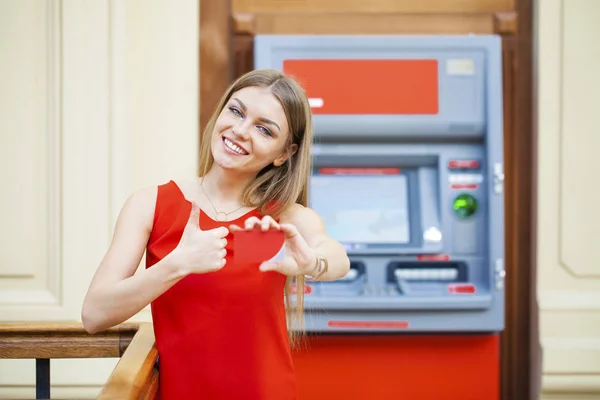 Atm でクレジット カードからお金を引き出す幸せな金髪女 — ストック写真