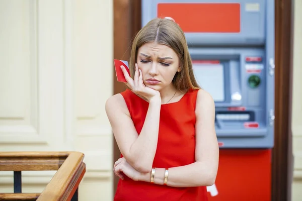 Frustrated young woman stands on against ATM — Stock Photo, Image