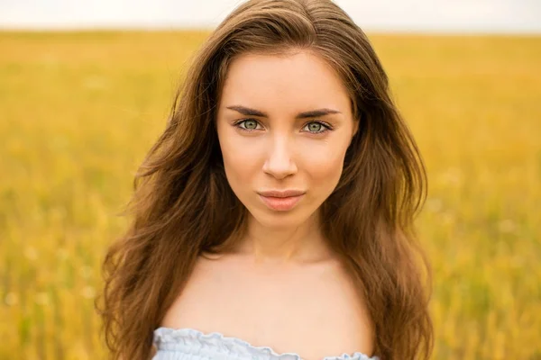 Jonge vrouw op een achtergrond van gouden tarweveld — Stockfoto