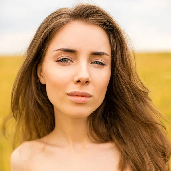 Jonge vrouw op een achtergrond van gouden tarweveld — Stockfoto