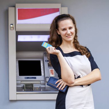 Young woman inserting a credit card to ATM clipart