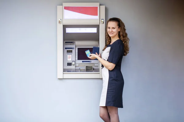 Young woman inserting a credit card to ATM — Stock Photo, Image