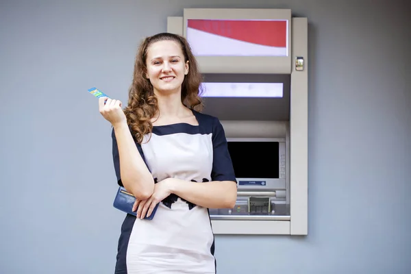 Mujer joven insertando una tarjeta de crédito en el cajero automático —  Fotos de Stock