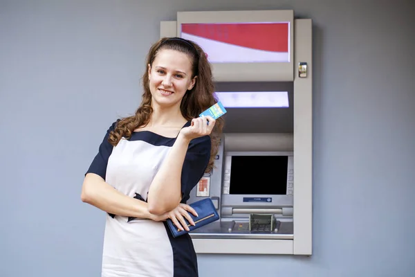 Mujer joven insertando una tarjeta de crédito en el cajero automático —  Fotos de Stock