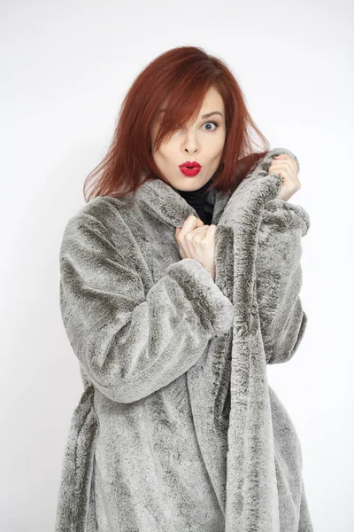 Jeune belle femme aux cheveux rouges en manteau de fourrure gris en artifici — Photo