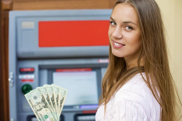 Genç sarışın kadın bir nakit dolar tutuyor — Stok fotoğraf