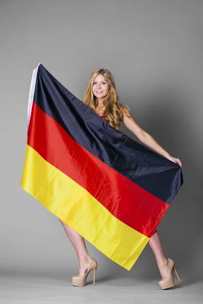 Красивая женщина, завернутая в немецкий флаг — стоковое фото