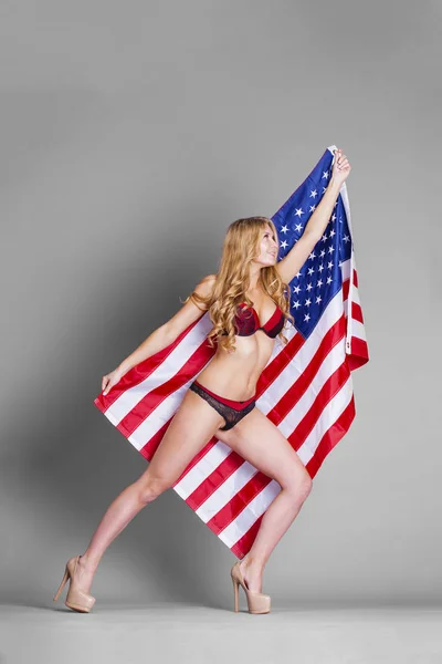 Young beautiful woman in red lingerie holding American flag — Stock Photo, Image