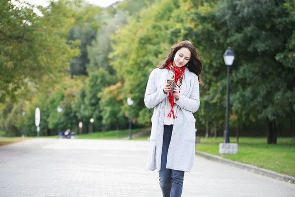 Portrait of happy young brunette woman in gray coat talking on t — Stock Photo, Image