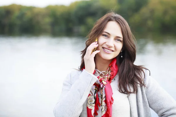 Portret van gelukkige jonge brunette vrouw beige jas om te praten over — Stockfoto