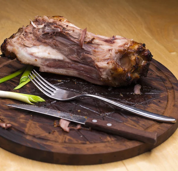 Pork bone with knife and fork, leftovers on a table after big di — Stock Photo, Image